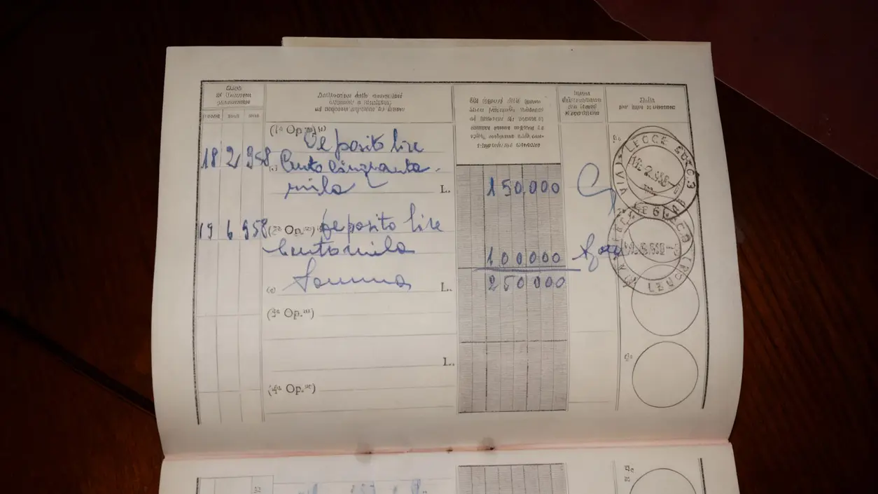 Pagina interna di un vecchio libretto postale con annotazioni manoscritte e timbri postali.